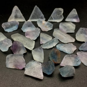 May include: A collection of fluorite crystals in various shades of blue, purple, and green. The crystals are rough and have a natural, unpolished look.