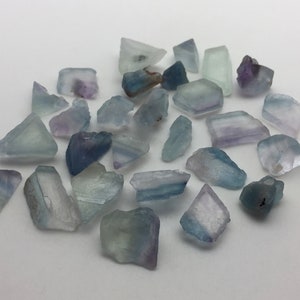 May include: A collection of small, rough, blue, green, and purple fluorite crystals. The crystals are various shapes and sizes.