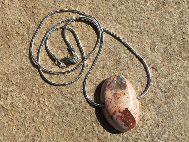 Op de afbeelding: Een zilveren ketting met een ovale hanger van roze en bruine opaal.