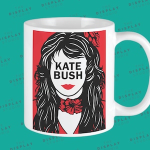 May include: White ceramic mug with a red background and a black and white illustration of Kate Bush. The text "Kate Bush" is printed in black letters on the mug.