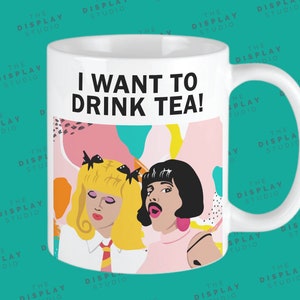 May include: White ceramic mug with a black and white illustration of two women with the text "I want to drink tea!" printed on the front.