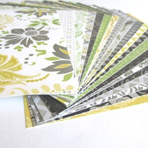 May include: A fan of patterned paper in various shades of yellow, green, and gray. The papers feature different geometric and floral designs.