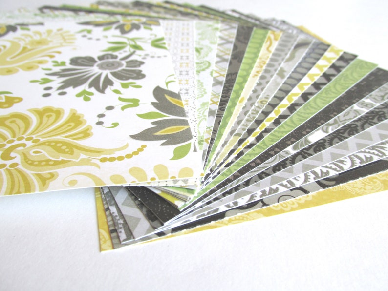 May include: A fan of patterned paper in various shades of yellow, green, and gray. The papers feature different geometric and floral designs.