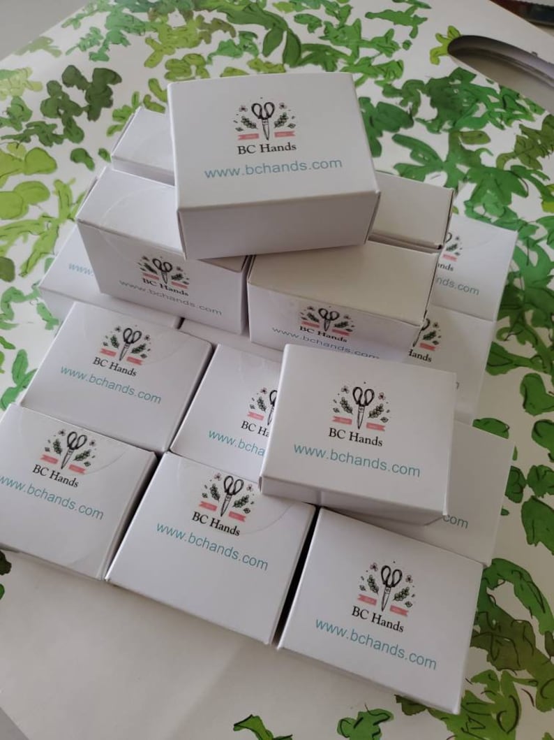 May include: A stack of white boxes with a logo of scissors and the text "BC Hands" and the website address "www.bchands.com" printed on each box.