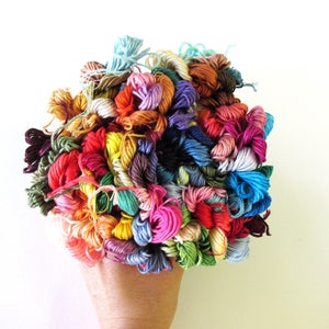 May include: A large collection of colorful embroidery floss spools in various shades of red, blue, green, yellow, orange, pink, purple, and brown.