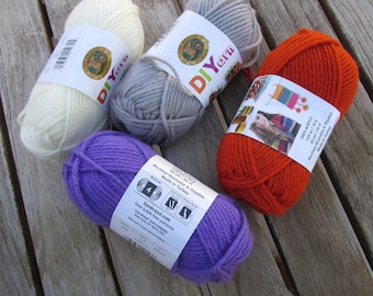 May include: Four skeins of yarn in different colors: white, gray, orange, and purple. The yarn is labeled "DIY yarn" and is machine washable and dryable. The yarn is made in Turkey.
