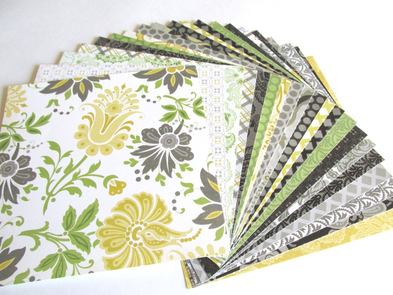 May include: A stack of patterned scrapbook paper in shades of green, yellow, and gray. The paper features various floral and geometric designs.