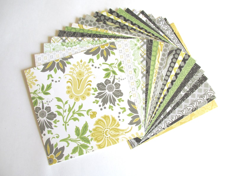 May include: A fan of patterned paper squares in shades of green, yellow, and gray. The papers feature various floral and geometric designs.