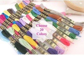 Puede incluir: Una colección de 20 colores diferentes de hilo para bordar. El hilo está dispuesto en una fila, con los colores que van de claro a oscuro. El hilo está etiquetado con números, y el texto "Choose 20 Colors" es visible en la imagen.