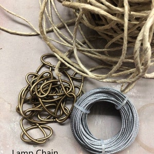 May include: A close-up of three different types of cord: hemp cord, lamp chain, and aviation wire. The hemp cord is a natural beige color, the lamp chain is gold, and the aviation wire is silver.