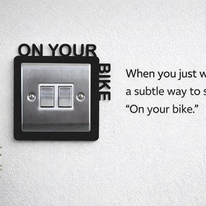 May include: A black decorative light switch cover with the words "ON YOUR BIKE" and a stainless steel switch plate. The text "When you just want a subtle way to say 'On your bike'" is also visible.