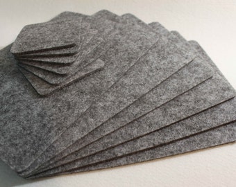 May include: A set of gray felt coasters, including a stack of square coasters and a stack of hexagonal coasters.