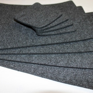 May include: A set of gray felt coasters and placemats. The coasters are square and the placemats are rectangular.
