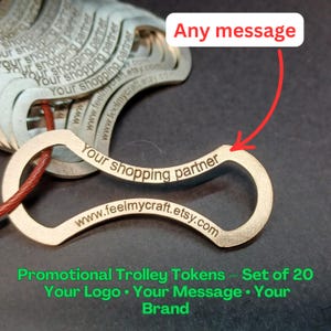 Op de afbeelding: Een stapel zilverkleurige promotionele winkelwagenmuntjes met de tekst "Your shopping partner" en "www.feelmycraft.etsy.com" gegraveerd. De muntjes zijn verbonden door een rood touwtje. De tekst "Any message" staat erboven.