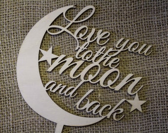 May include: Wooden cake topper with the phrase "Love you to the moon and back" in a cursive font. The design includes a crescent moon and two stars. The topper is made of light-colored wood.