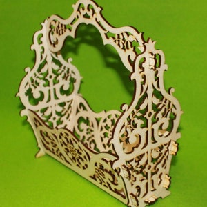 Op de afbeelding: Een decoratieve houten mand met ingewikkelde uitgesneden ontwerpen. De mand heeft een handvat en is gemaakt van licht hout.
