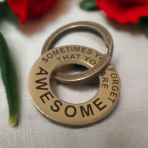 May include: Gold-toned metal keychain with a round charm that reads "Sometimes you forget that you are awesome".