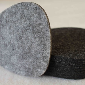 May include: A stack of grey felt circles, one of which is a slightly larger, triangular shape.