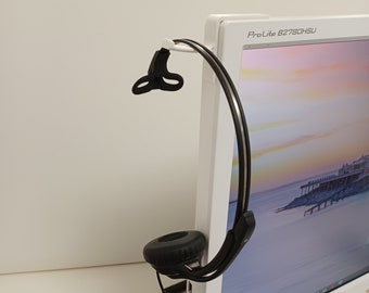 Op de afbeelding: Een zwarte headset met een microfoon is bevestigd aan een witte computermonitor. De monitor heeft de tekst "ProLite B2780HSU" aan de voorkant.