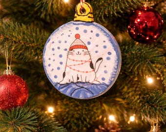 Cat with hat tangled in garland ornament