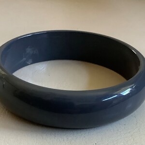 May include: A simple, solid, gray plastic bangle bracelet.