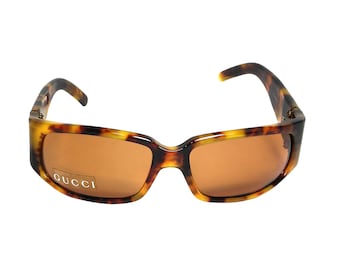 Puede incluir: Gafas de sol de carey con lentes marrones y la palabra "GUCCI" impresa en la montura.