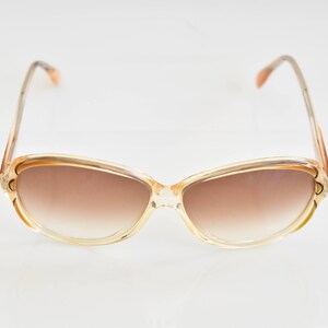 Könnte beinhalten: Eine Sonnenbrille mit braunem Farbverlauf und einem transparenten Kunststoffgestell.