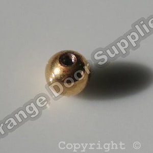 May include: A gold-colored metal ball with a threaded hole in the center.