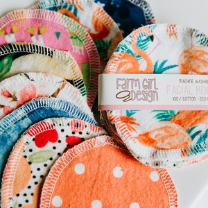 May include: A stack of colorful reusable cotton facial rounds with a label that reads "Farm Girl Design Machine Washable Facial Rounds 100% Cotton Eco Friendly".