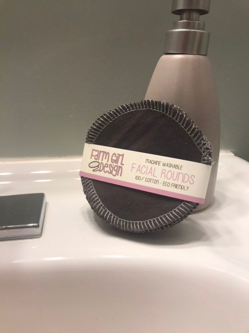 May include: A stack of dark gray reusable cotton facial rounds with a pink and white label that reads "Farm Girl Design" and "Machine Washable Facial Rounds 100% Cotton - Eco Friendly".