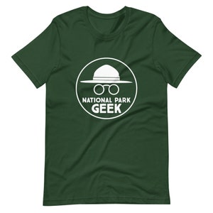 May include: A green t-shirt with a white circle graphic. The graphic features a ranger hat, glasses, and the text "National Park Geek".