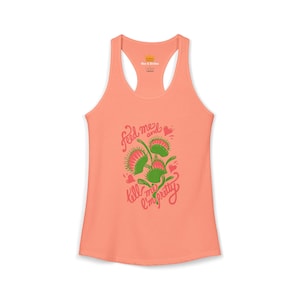 May include: A peach-colored racerback tank top featuring a graphic of three green and red Venus flytrap plants. The text "feed me and tell me I'm pretty" is printed in red script around the plants, accompanied by small red heart illustrations.