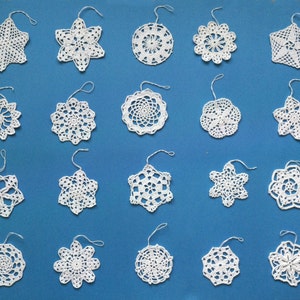May include: Twenty white crocheted snowflakes on a blue background. Each snowflake has a loop at the top for hanging.