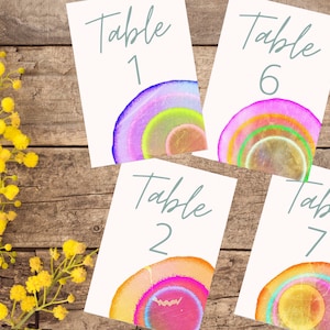 May include: Four table number cards with colorful agate designs. The cards are white with gray text that reads "Table 1", "Table 2", "Table 6", and "Table 7".