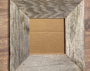 May include: Square wooden picture frame with a rustic, weathered appearance. The frame is made of gray-toned wood with visible grain and texture. The center opening is empty, revealing a cardboard backing. The frame is designed to hold a photograph or artwork.