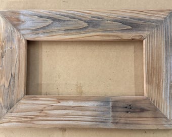 May include: Rectangular wooden picture frame with a natural, weathered appearance. The frame is made of light brown wood with gray and darker brown streaks, showcasing the wood grain. The frame's corners are joined at 90-degree angles.