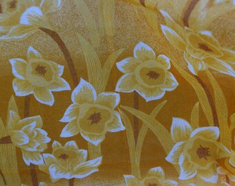 May include: A yellow fabric with a white floral pattern of daffodils. The fabric has a subtle sheen and a textured surface.
