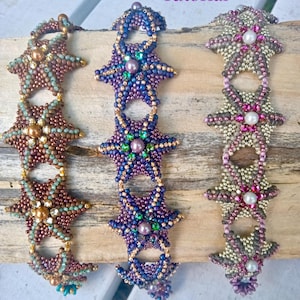 May include: Three beaded bracelets with starfish designs. The bracelets are in shades of brown, purple, and pink, with pearl accents. The text "Seashore Bliss" and "Tutorial" are at the top, and "Agnieszka Watts" is at the bottom.