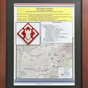 May include: Framed print featuring the 20th Engineer Brigade and 19th Engineer Battalion. The print includes a map of Afghanistan, a unit patch, and text detailing operations and the order of battle. The frame is brown.