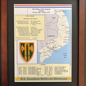 May include: Framed print of the 18th Military Police Brigade in Vietnam, 1966-1973. Includes a map of Vietnam, unit patches, and campaign details. The frame is a dark brown color.