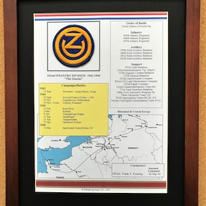 May include: Framed print of the 102nd Infantry Division, 1942-1945, featuring a patch with a blue "Z" in a yellow circle. Includes a map of Rhineland & Central Europe, campaign dates, and the order of battle. The print is in a dark brown frame.