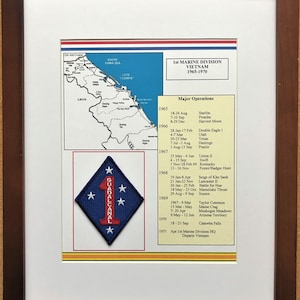 May include: Framed print featuring a map of Vietnam and a patch with the text "GUADALCANAL" and the number "1". The print includes a list of major operations from 1965-1970. The frame is a dark brown color.