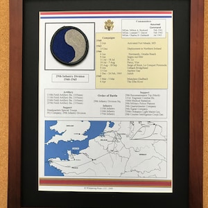 May include: Framed print featuring the 29th Infantry Division emblem, a blue and gray yin-yang symbol. The print includes a list of campaigns, commanders, and an order of battle, along with a map of Europe. The frame is dark brown.