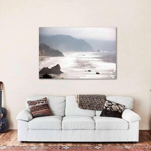 May include: A misty seascape photograph with a coastline and waves crashing on the shore. The image is in shades of gray and white, with a soft, ethereal feel.