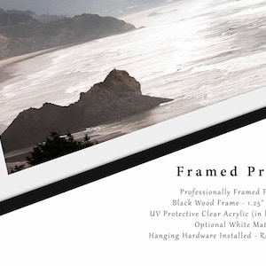 May include: A framed print of a coastal landscape with a rocky outcropping and ocean waves. The frame is black wood with a 1.25 inch width and a clear acrylic protective layer. It includes an optional white mat and hanging hardware.