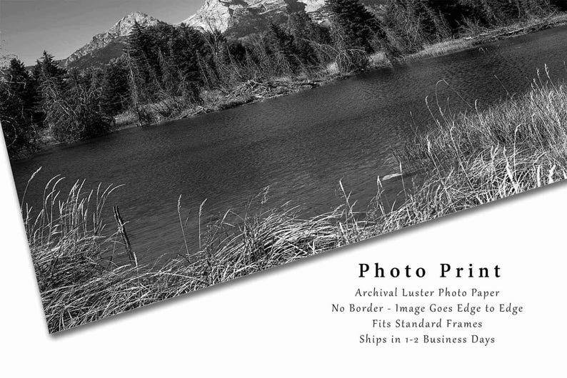 May include: Black and white photograph of a mountain lake with trees and mountains in the background. The image is printed on archival lustre photo paper with no border. The image goes edge to edge and fits standard frames. Ships in 1-2 business days.