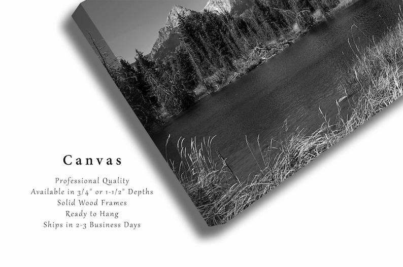 May include: Black and white photograph of a mountain lake with trees and snow-capped mountains in the background. The image is printed on canvas and ready to hang.
