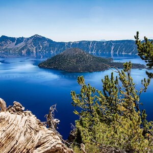 May include: A panoramic view of Crater Lake in Oregon, a deep blue lake surrounded by forested hills and a small island in the center.