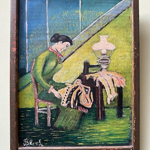 May include: An oil painting in a dark wooden frame depicts a woman in a green dress and red scarf seated at a table, sewing. A lamp sits on the table, and a window with a blue sky is in the background. The painting is signed "Bloch".