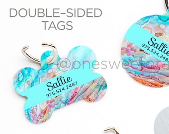 May include: Two double-sided pet ID tags with a turquoise and orange abstract design. The tags are shaped like a bone and a circle. The text "Sallie" and a phone number are printed on both tags.